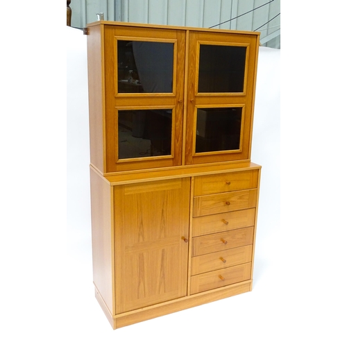 834 - Two c1970s teak cupboards, each consisting of a glazed (tinted) shelving unit above a floor standing... 