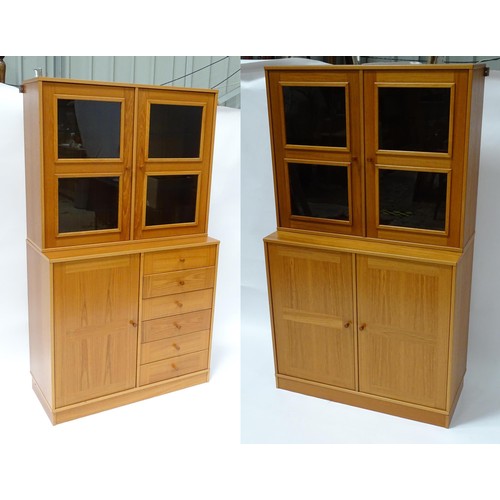 834 - Two c1970s teak cupboards, each consisting of a glazed (tinted) shelving unit above a floor standing... 