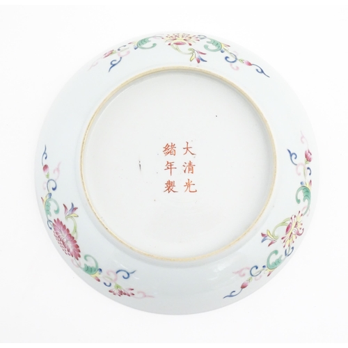 33 - A Chinese famille rose plate decorated with three dragons and a flaming pearl amongst stylised cloud... 