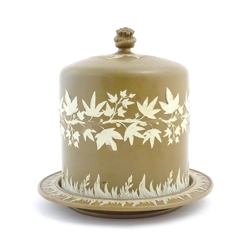 152 - A Wedgwood Jasperware style brown and white cheese dome with foliate decoration, the cover with hay ... 