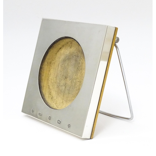 276 - An easel back photograph frame of squared form with a silver surround hallmarked Sheffield 2000, mak... 