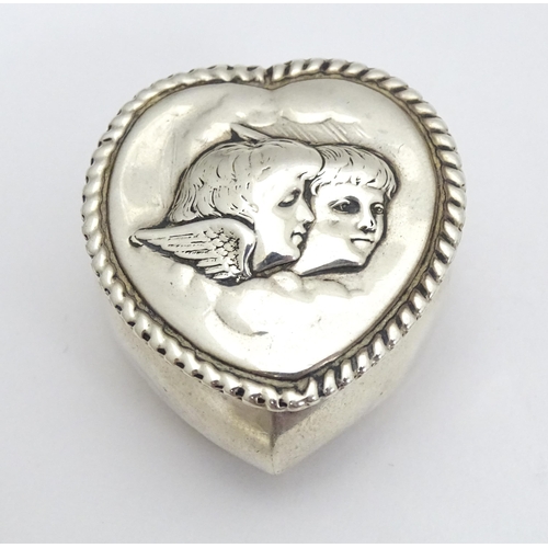 320 - A Victorian silver pill box of heart shape with hinged lid and embossed angel / cherub detail to top... 