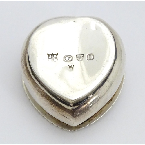 320 - A Victorian silver pill box of heart shape with hinged lid and embossed angel / cherub detail to top... 