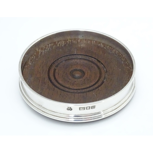 333 - A small silver coaster with a turned wooden base, hallmarked London 1990 maker M C Hersey & Son Ltd.... 