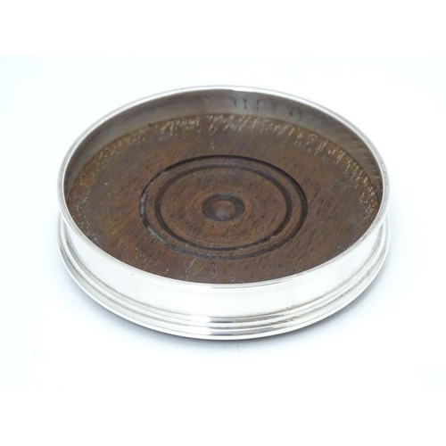 333 - A small silver coaster with a turned wooden base, hallmarked London 1990 maker M C Hersey & Son Ltd.... 