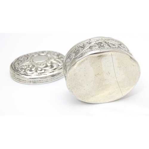 348 - A white metal pill box of oval form with embossed decoration. Approx. 1 3/4