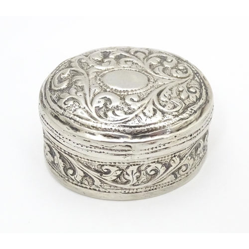 348 - A white metal pill box of oval form with embossed decoration. Approx. 1 3/4