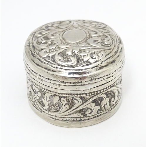 348 - A white metal pill box of oval form with embossed decoration. Approx. 1 3/4