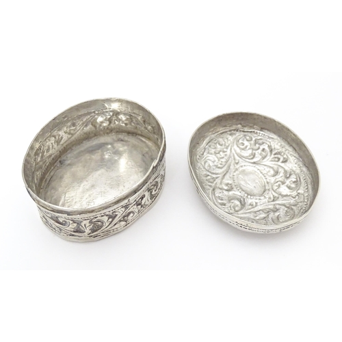 348 - A white metal pill box of oval form with embossed decoration. Approx. 1 3/4