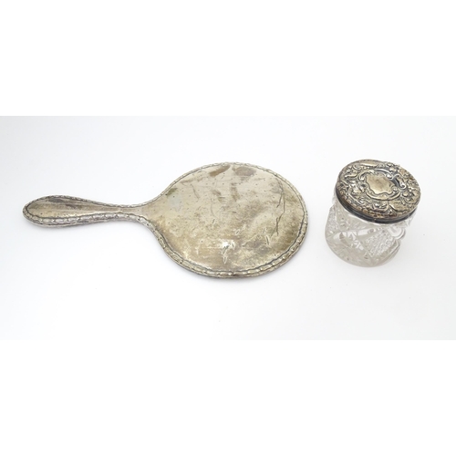 349 - A silver hand mirror and together with a silver topped glass dressing table pot. 2 1/2