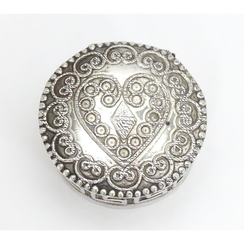 392 - A white metal pill box of circular form heart detail to lid. Approx. 1 1/4