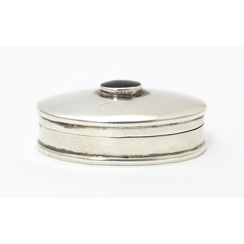 393 - A silver pill box of oval form with inset  coloured cabochon to top. Approx. 1 1/4