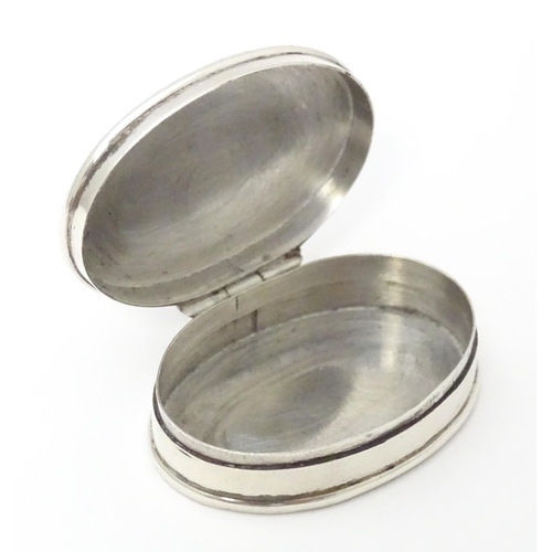 393 - A silver pill box of oval form with inset  coloured cabochon to top. Approx. 1 1/4