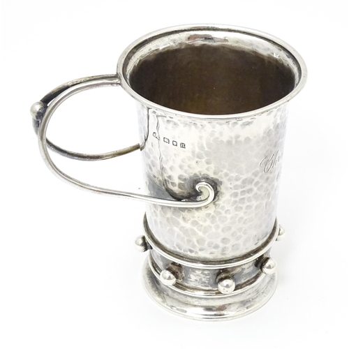 404 - An Arts & Crafts silver christening mug with hammered decoration, banded spherical ball detail and b... 