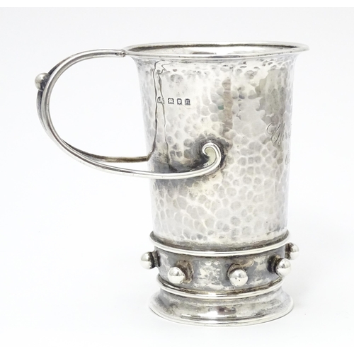 404 - An Arts & Crafts silver christening mug with hammered decoration, banded spherical ball detail and b... 