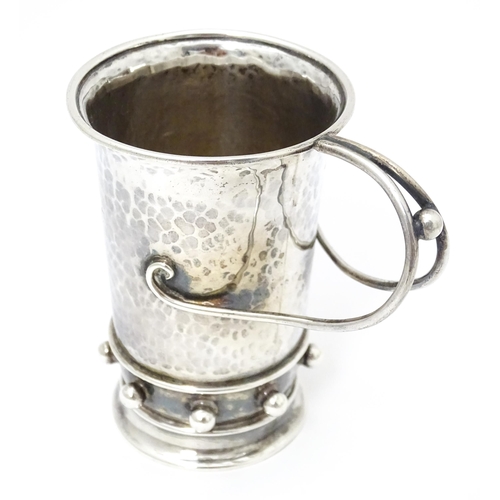 404 - An Arts & Crafts silver christening mug with hammered decoration, banded spherical ball detail and b... 