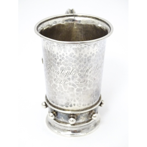 404 - An Arts & Crafts silver christening mug with hammered decoration, banded spherical ball detail and b... 