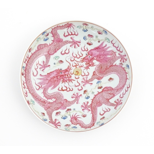 17 - A Chinese famille rose dragon dish with two dragons, flaming pearl and stylised clouds. The reverse ... 