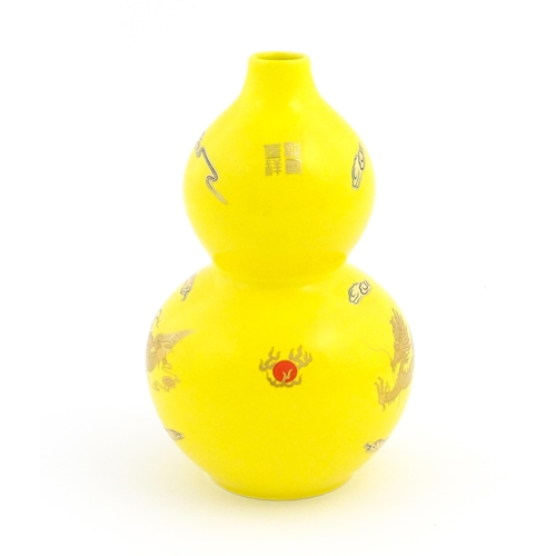 54 - A Chinese double gourd vase with a yellow ground decorated with dragons and a flaming pearl. Charact... 