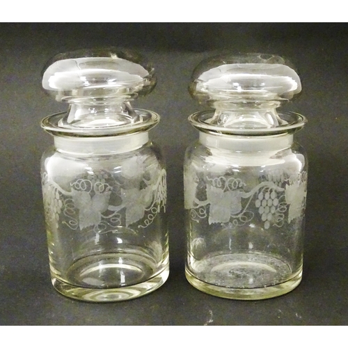 208 - Two glass jars and stoppers decorated with etched fruiting vine detail. Approx 5 3/4