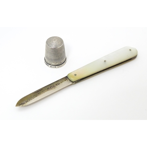 563 - A silver thimble hallmarked 1972 maker James Swann & Son together with a silver folding fruit knife ... 