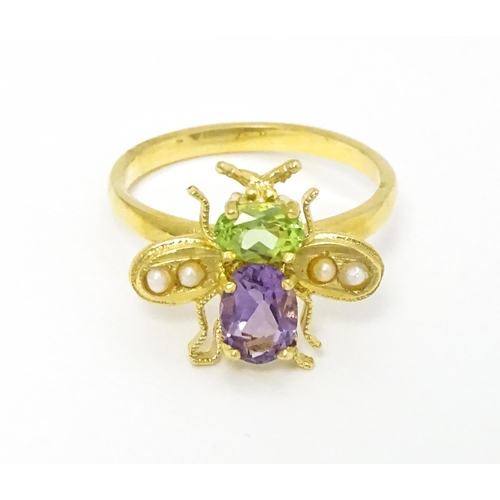 642 - A silver gilt ring with bee / winged insect decoration set with amethyst, pearl and peridot. Ring si... 