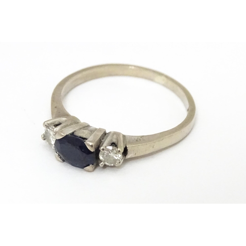 645 - An 18ct white gold ring set with central sapphire flanked by diamonds. Ring size approx. M 1/2