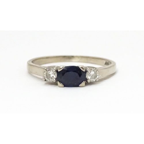 645 - An 18ct white gold ring set with central sapphire flanked by diamonds. Ring size approx. M 1/2