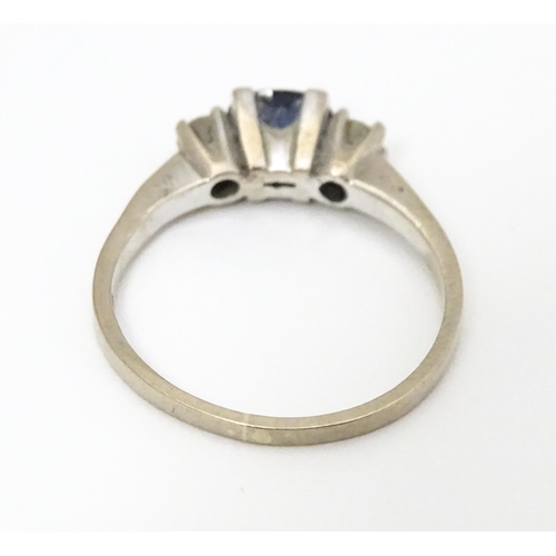 645 - An 18ct white gold ring set with central sapphire flanked by diamonds. Ring size approx. M 1/2