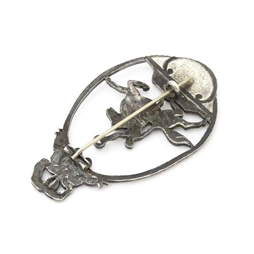 694 - A white metal brooch of oval form with image to centre depicting man on horseback holding aloft a la... 