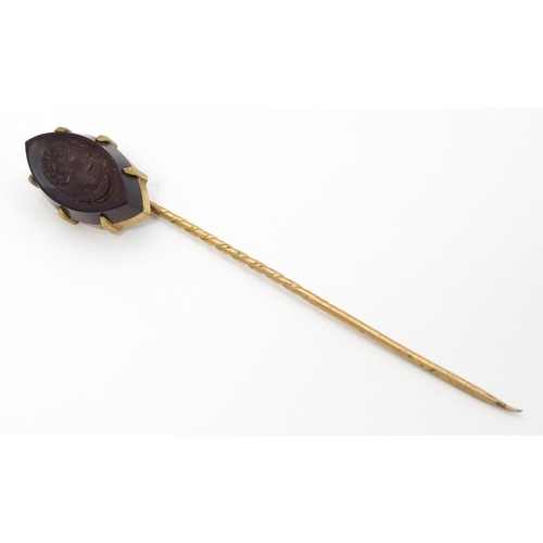 719 - A yellow metal stick pin with carved intaglio to top. Approx 2 3/4