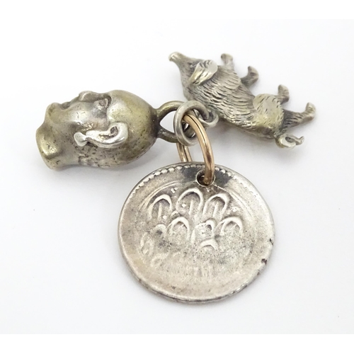 748 - Three assorted charms to include a white metal model of a pig / boar, a buddha head and a coin fob f... 