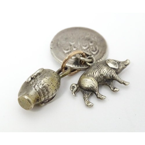 748 - Three assorted charms to include a white metal model of a pig / boar, a buddha head and a coin fob f... 