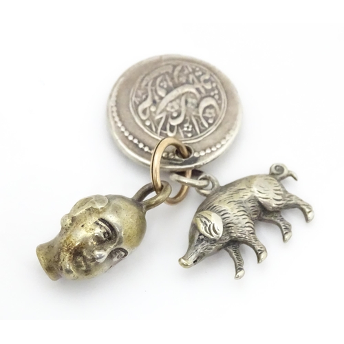 748 - Three assorted charms to include a white metal model of a pig / boar, a buddha head and a coin fob f... 