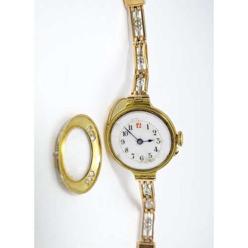 766 - An 18ct gold cased ladies wristwatch set with 12 diamonds, with white enamel dial, and 15ct gold bra... 