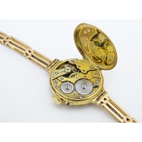 766 - An 18ct gold cased ladies wristwatch set with 12 diamonds, with white enamel dial, and 15ct gold bra... 