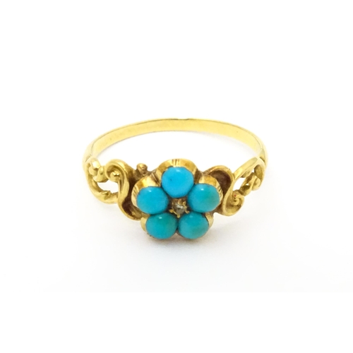 610 - A yellow metal ring set with central diamond bordered by turquoise. Ring size approx K