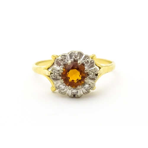 612 - An 18ct gold ring set with central red tourmaline bordered by diamonds. Ring size approx. R