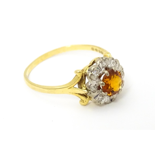 612 - An 18ct gold ring set with central red tourmaline bordered by diamonds. Ring size approx. R