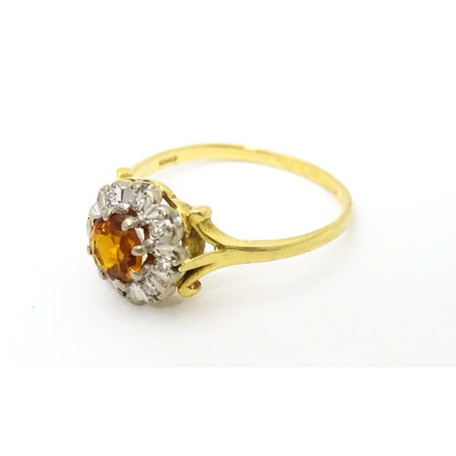 612 - An 18ct gold ring set with central red tourmaline bordered by diamonds. Ring size approx. R