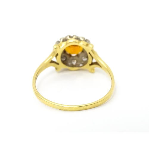 612 - An 18ct gold ring set with central red tourmaline bordered by diamonds. Ring size approx. R