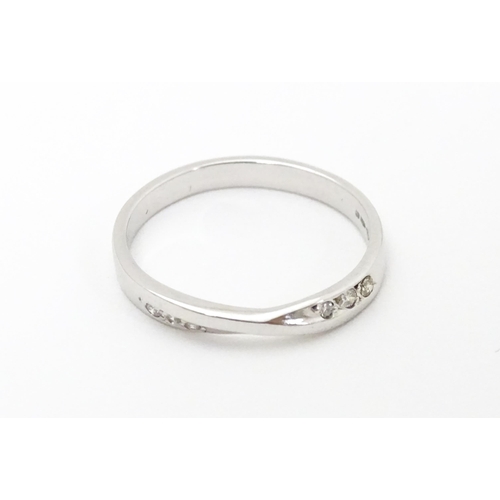619 - A platinum ring with central twist flanked by three diamonds. Ring size approx. N