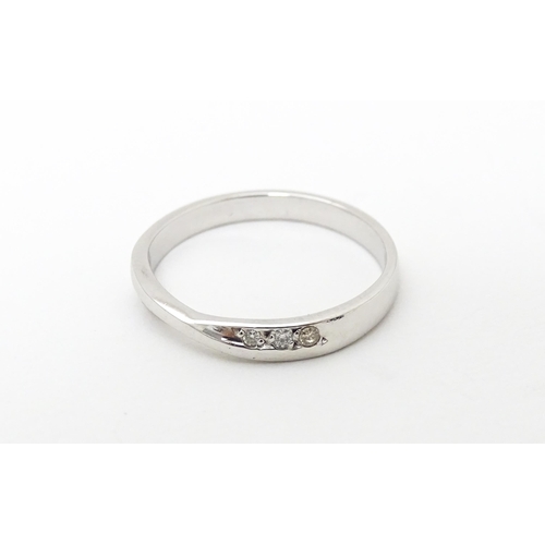 619 - A platinum ring with central twist flanked by three diamonds. Ring size approx. N