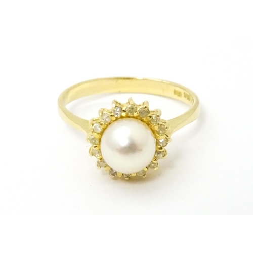 622 - A 14ct gold ring set with central pearl bordered  by diamonds. Ring size approx. M