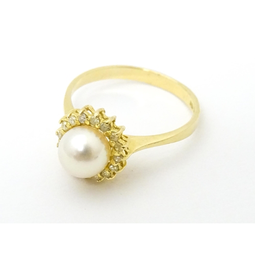 622 - A 14ct gold ring set with central pearl bordered  by diamonds. Ring size approx. M