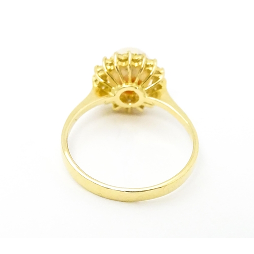 622 - A 14ct gold ring set with central pearl bordered  by diamonds. Ring size approx. M