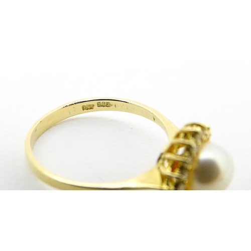 622 - A 14ct gold ring set with central pearl bordered  by diamonds. Ring size approx. M