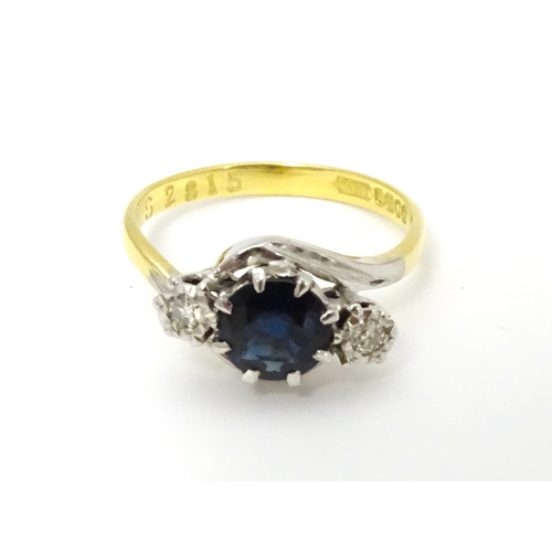 634 - An 18ct gold ring with platinum set central sapphire flanked by two diamonds. Ring size approx. M 1/... 