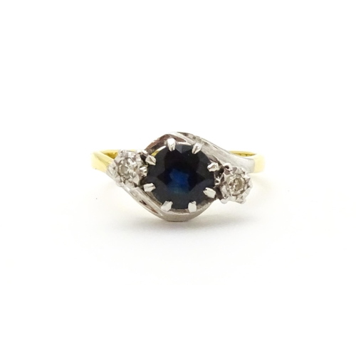 634 - An 18ct gold ring with platinum set central sapphire flanked by two diamonds. Ring size approx. M 1/... 