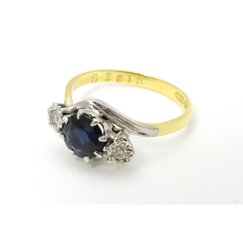 634 - An 18ct gold ring with platinum set central sapphire flanked by two diamonds. Ring size approx. M 1/... 